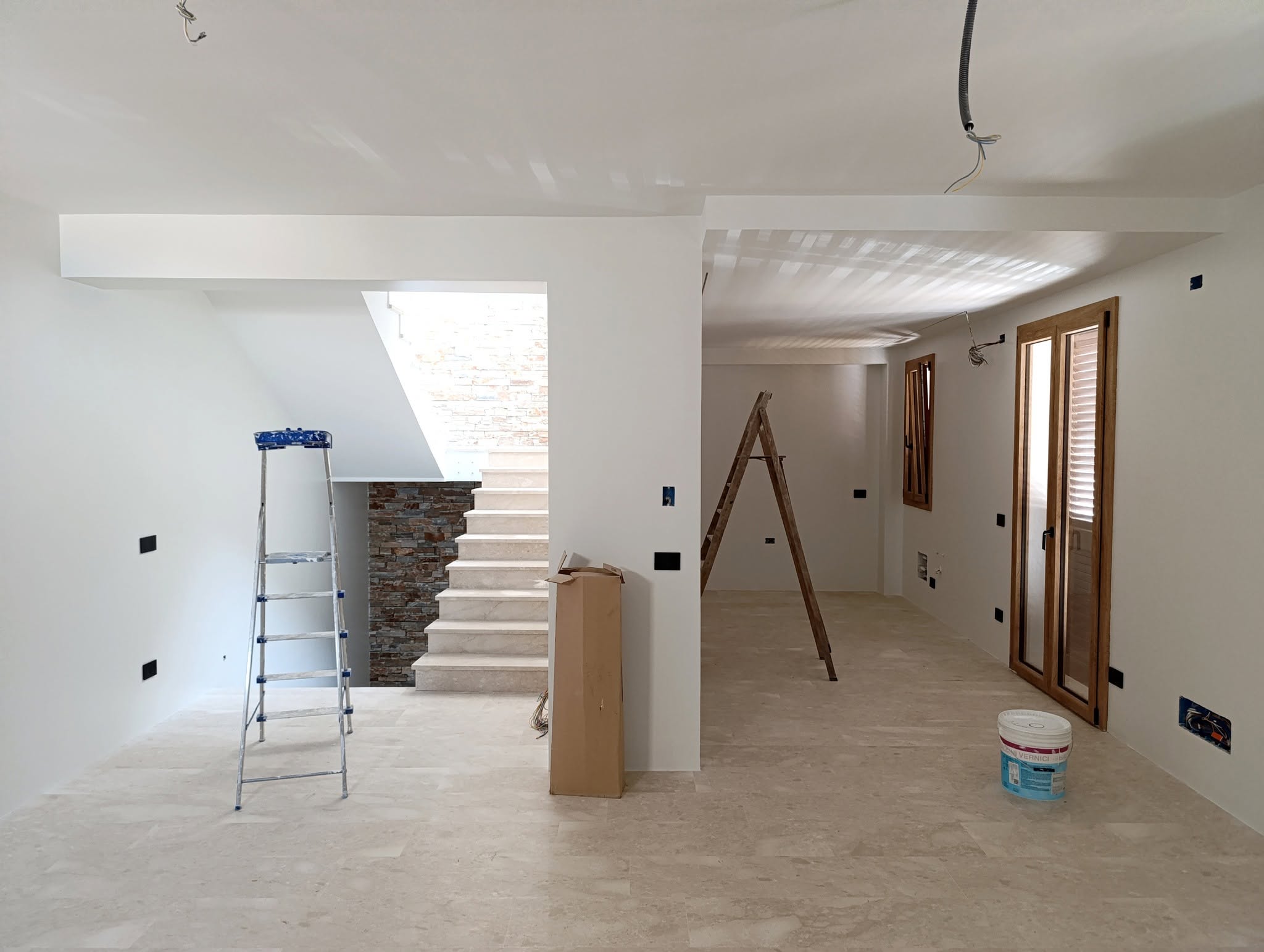 Interno in fase di finitura con scala in pietra e infissi in legno